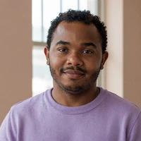 Portrait of Marcus, a Black little person community member, smiling gently