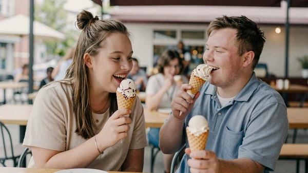 Young adult couple with Down syndrome sharing ice cream at a cafe